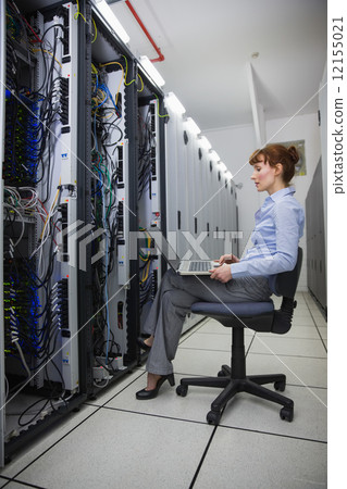 Technician sitting on swivel chair using laptop to diagnose serv Technician sitting on swivel chair using laptop to diagnose serv 12155021