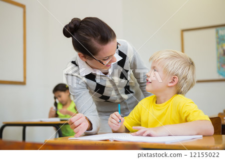 Pretty teacher helping pupil in classroom Pretty teacher helping pupil in classroom 12155022