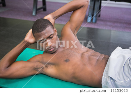 Shirtless man doing abdominal crunches in gym Shirtless man doing abdominal crunches in gym 12155023