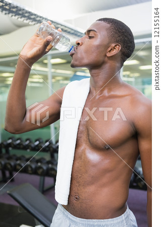 Shirtless man drinking water at gym 12155164