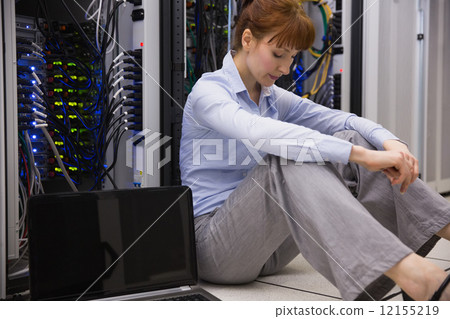 Stressed technician sitting on floor beside open server 12155219