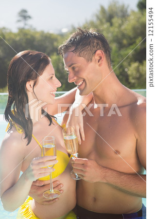 Couple with champagne flutes by swimming pool 12155494
