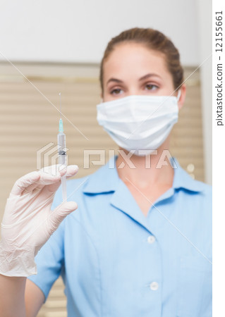 Dental assistant holding injection looking at it Dental assistant holding injection looking at it 12155661