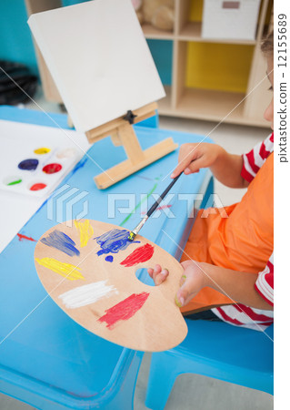 Cute little boy painting at table in classroom 12155689