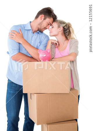 Attractive young couple leaning on boxes with piggy bank Attractive young couple leaning on boxes with piggy bank 12155691