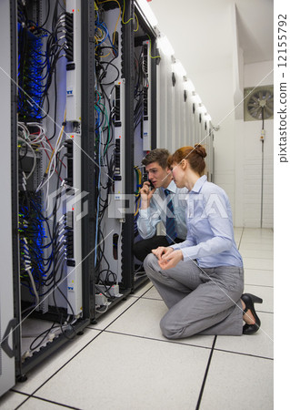 Team of technicians kneeling and looking at servers Team of technicians kneeling and looking at servers 12155792