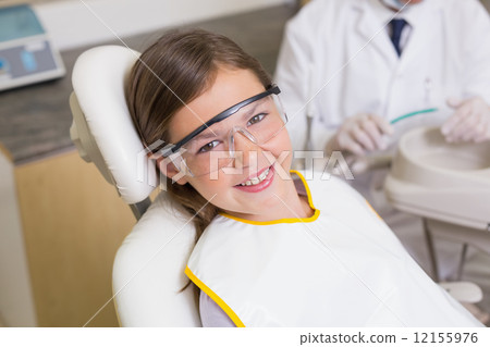 Little girl sitting in dentists chair wearing protective glasses 12155976