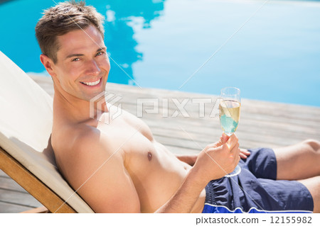 Man holding champagne flute by the swimming pool 12155982