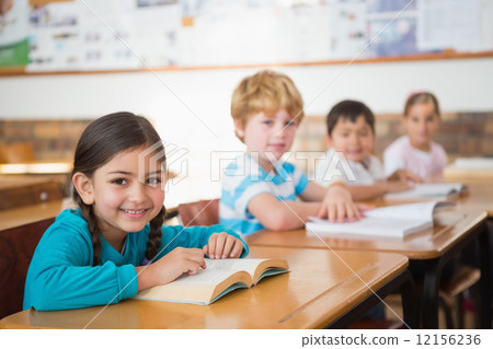 Pupils sitting in classroom reading books