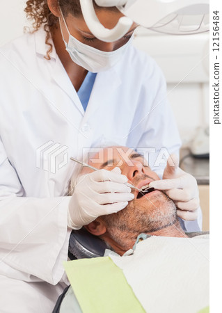 Dentist examining a patients teeth in the dentists chair Dentist examining a patients teeth in the dentists chair 12156484