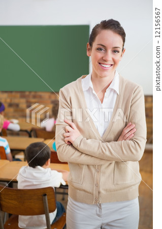 Pretty teacher smiling at camera at back of classroom Pretty teacher smiling at camera at back of classroom 12156567