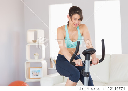 Fit brunette working out on exercise bike 12156774