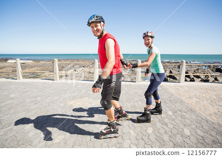 Fit mature couple rollerblading on the pier 12156777