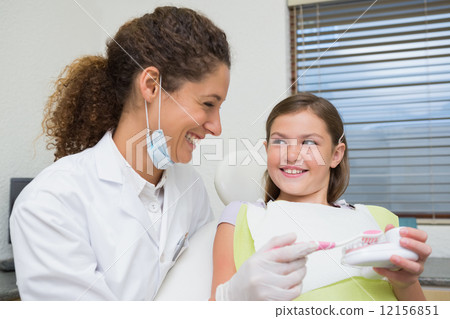 Pediatric dentist showing little girl how to brush her teeth 12156851