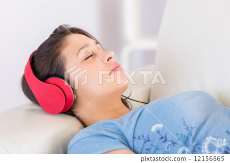 Pretty brunette listening to music on the couch Pretty brunette listening to music on the couch 12156865