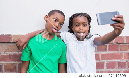 Cute pupils taking a selfie in the corridor 12156899