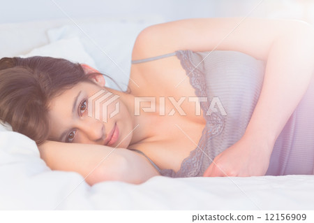 Beautiful brunette lying on bed smiling at camera Beautiful brunette lying on bed smiling at camera 12156909