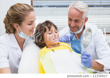 Pediatric dentist showing little boy his teeth in the mirror 12156927