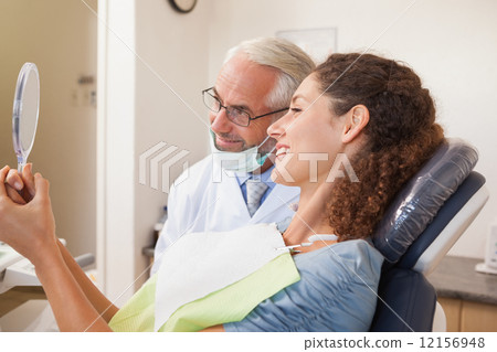 Patient admiring her new smile in the mirror 12156948