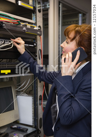 Stock Photo: Pretty computer technician talking on phone while fixing server