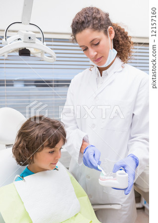 Pediatric dentist showing little boy teeth model 12157160