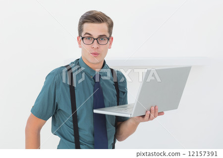 Nerdy businessman holding laptop looking at camera Nerdy businessman holding laptop looking at camera 12157391