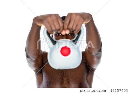 Shirtless fit young man lifting kettle bell 12157403