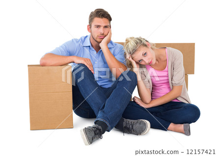 Unhappy young couple sitting beside moving boxes 12157421