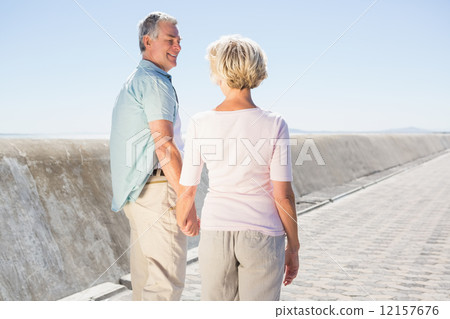 Senior couple holding hands and walking Senior couple holding hands and walking 12157676