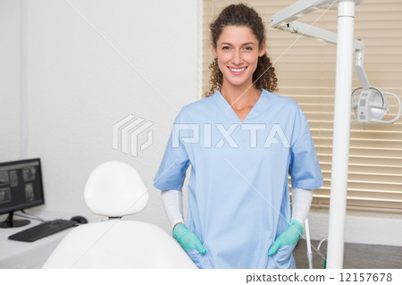 Dentist in blue scrubs smiling at camera Dentist in blue scrubs smiling at camera 12157678