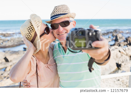 Happy casual couple taking a selfie by the coast 12157679