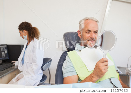 Patient admiring his new smile in the mirror 12157683