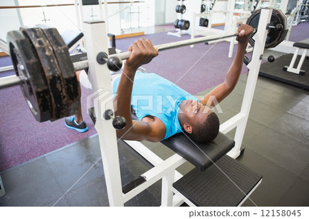 Determined young man lifting barbell in gym Determined young man lifting barbell in gym 12158045