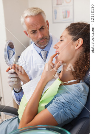Patient showing dentist the problem in the mirror 12158150