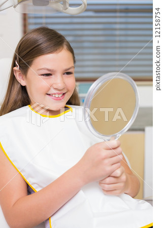 Little girl holding mirror in dentists chair 12158754