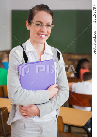 Pretty teacher smiling at camera at back of classroom 12158797
