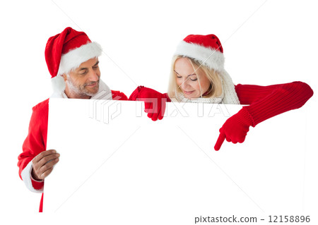 Festive couple pointing to large white card 12158896