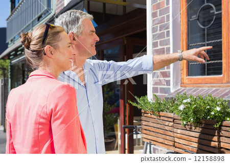 Happy senior couple shopping and pointing in the city 12158898