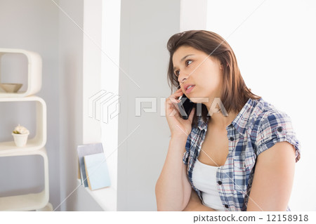 Pretty brunette sitting beside her window talking on phone Pretty brunette sitting beside her window talking on phone 12158918