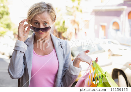 Happy mature woman smiling at camera with her shopping purchases Happy mature woman smiling at camera with her shopping purchases 12159155