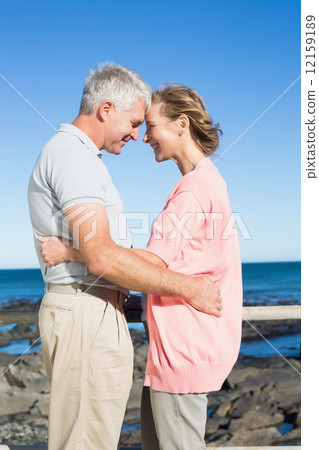 Happy casual couple smiling at each other by the coast Happy casual couple smiling at each other by the coast 12159189