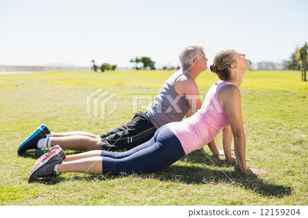 Fit mature couple warming up on the grass 12159204