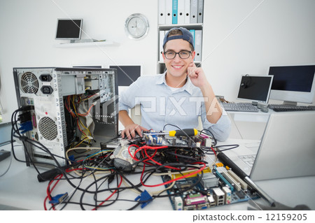 Smiling technician working on broken computer Smiling technician working on broken computer 12159205