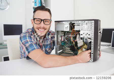 Computer engineer working on broken console smiling at camera Computer engineer working on broken console smiling at camera 12159206