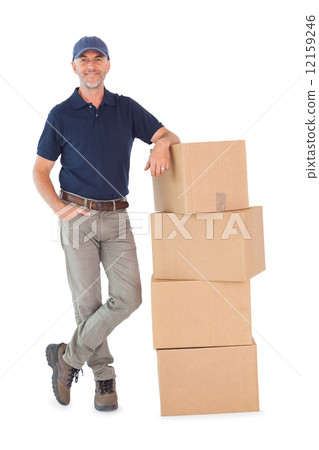 Happy delivery man leaning on pile of cardboard boxes 12159246