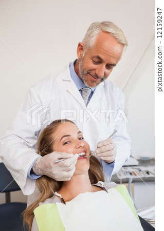Dentist examining a patients teeth in the dentists chair Dentist examining a patients teeth in the dentists chair 12159247