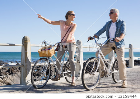 Happy casual couple going for a bike ride on the pier 12159444
