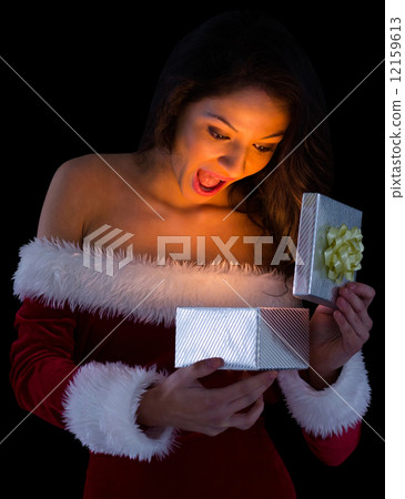 Pretty brunette in santa outfit opening gift 12159613