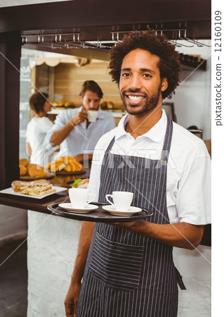 Handsome waiter smiling at camera holding tray Handsome waiter smiling at camera holding tray 12160109