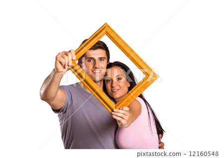 Young couple holding up frame 12160548